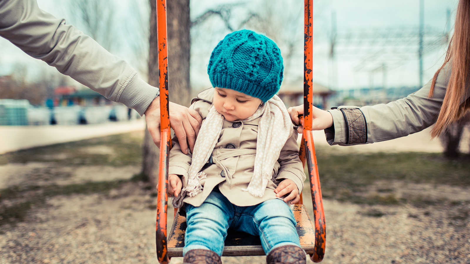 Sad child on a swing, inbetween her divorced parents holding her separatedly .